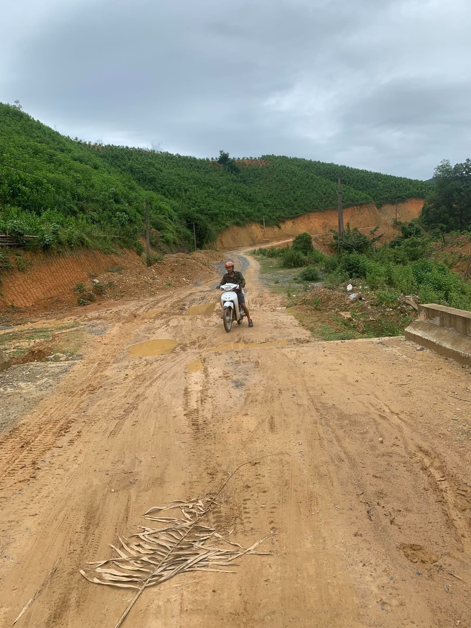Motorbike rider on a muddy road through green hills in rural Vietnam