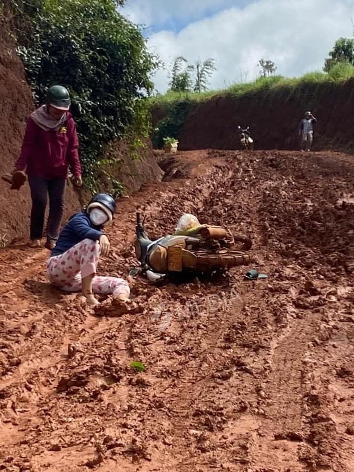 Loaded motorbike lying on its side on a deeply rutted muddy road